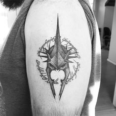 a black and white photo of a man's arm with a compass tattoo on it