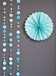 a blue and white paper decoration hanging from the ceiling next to a wall with circles on it