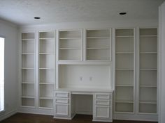 an empty room with built in bookshelves and desk