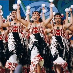 a group of men and women in native garb dancing with pom poms