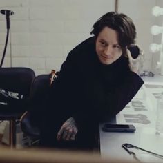 a man sitting at a desk with his hands on his head and looking off to the side