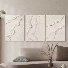 three white paintings hanging on the wall in a living room