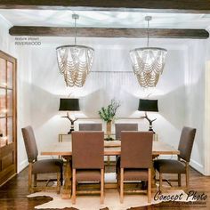 the dining room table is surrounded by brown chairs and two chandeliers hanging from the ceiling