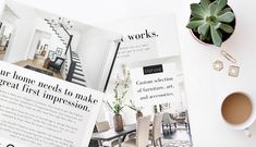 an open magazine sitting on top of a white table next to a cup of coffee