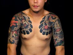 a man with many tattoos on his chest and arms is standing in front of a black background