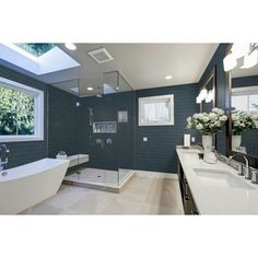 a bathroom with a tub, sink and large mirror in it's center area