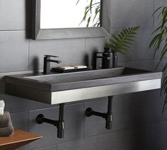 a bathroom sink sitting under a mirror next to a plant