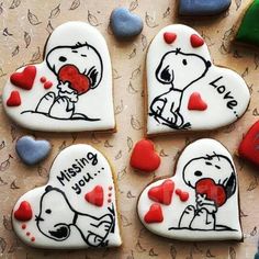 four decorated cookies in the shape of hearts with snoopy and charlie brown on them