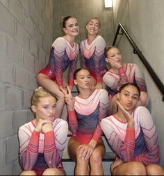 a group of young women sitting next to each other on top of stairs in front of a brick wall