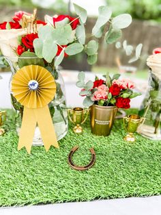 a table topped with vases filled with red flowers and greenery next to an award ribbon