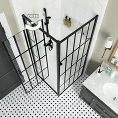 an open shower stall in a bathroom with black and white floor tiles on the walls