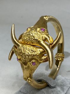 Stunning and rare vintage 18k yellow gold bracelet by the famed Greek designer, goldsmith Illias Lalaounis. Among his most famed work, you’ll find pieces from his timeless animal kingdom collection. The iconic collection includes this exquisite gold bangle bracelet with bull heads featuring dazzling ruby eyes and interlocked bull horns. The lustrous 18k yellow gold, craftsmanship and textural finishes makes this bracelet truly divine. It would make a sensational addition to any collection. Marked on interior - 750, Lalaounis mark is very worn but still can be seen 6 3/4" closed interior measurement 1.94" at it's widest at the top. Rubies - .20cttw Bull Taurus, Taurus Jewelry, Bull Horns, Greek Jewelry, Gold Bangle Bracelet, Yellow Gold Bracelet, Gold Bangles, Animal Kingdom, Bangle Bracelet