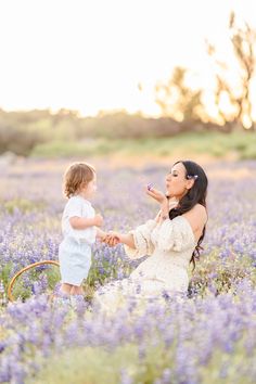 a mother and her child playing in a field of flowers