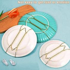 three white plates with wire on them sitting next to each other and two orange tulips