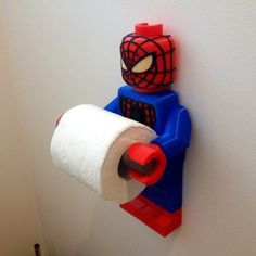 a spiderman toilet paper dispenser is on the wall next to a roll of toilet paper