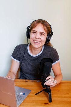 a woman sitting in front of a laptop computer wearing headphones and holding a microphone