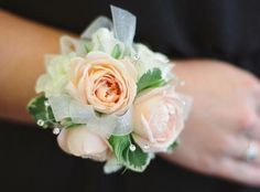 a bride's bouquet with peach roses and greenery is being held by her hands