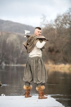 a man dressed in medieval clothing standing on a dock