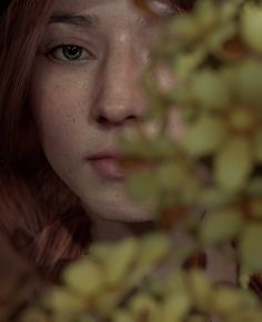 a close up of a person with red hair and green eyes looking at the camera