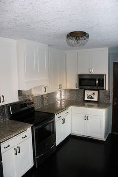 an empty kitchen with white cabinets and black counter tops is seen in this image from the doorway