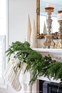 a christmas mantle decorated with evergreen, pine cones and stocking hanging from the mantel