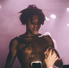 a man with dreadlocks standing in front of a microphone and holding a cell phone