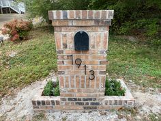 a brick mailbox sitting in the middle of a field