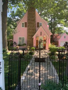 a pink house is behind a black iron fence and gated in area with flowers