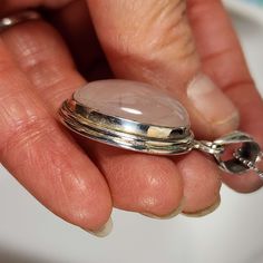 a person holding a silver locke with a stone in it's center and chain around the clasp