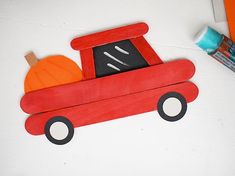 a red wooden toy truck with pumpkins in the back