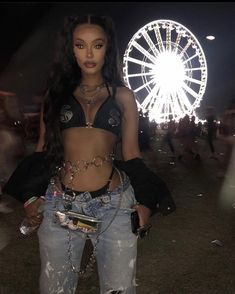 a woman standing in front of a ferris wheel at night with her hands on her hips