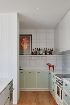 a kitchen with white walls and wooden floors is pictured in this image, there are many bottles on the counter