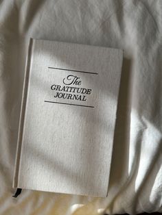 a book sitting on top of a bed next to a white sheet with the words the grateful journal