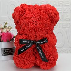 a red teddy bear made out of roses next to a flower pot