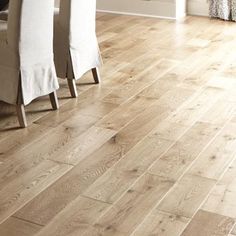 a wooden floor with white table cloths and chairs in the background on a hardwood floor