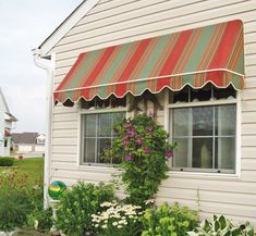 a white house with a red and green striped awning over it's windows