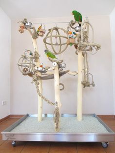 a metal frame with birds on it and ropes attached to the sides, in front of a white wall