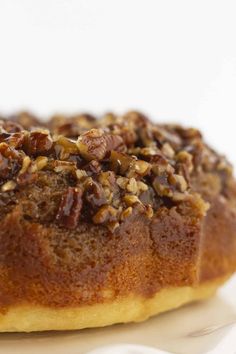 a bundt cake with pecans on top sitting on a white plate, ready to be eaten