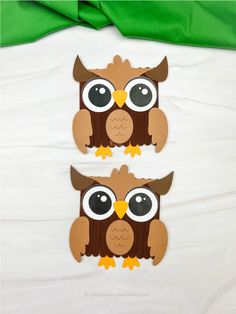 two brown owls with big eyes sitting next to each other on a white sheeted surface