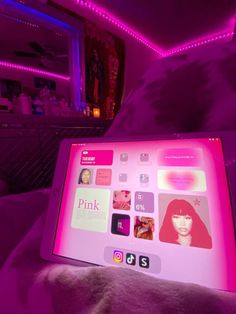 a laptop computer sitting on top of a bed covered in pink lights and stickers