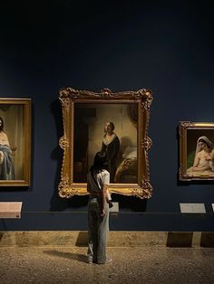 people looking at paintings on display in a museum