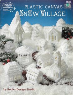 plastic canvass snow village book with white houses and trees in the snow, surrounded by pine cones