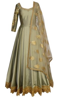 This set features a light olive green flared floor length suit in silk base with beautiful gold zari, cutdana, slight sequins and swarovski hand embroidery around the neckline and sleeves. It has a sheer back with matching dori tie up with gold tassleed hangings and gold zari and sequns embellished applique border. It is paired with a matching net dupatta with gold badla embellished all over botis and zari embellished border and comes with a matching churidar pants. This creation is designed ...