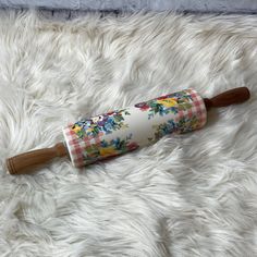 a wooden rolling pin sitting on top of a fluffy white rug next to a wall