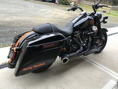 a black motorcycle parked on top of a cement road next to a parking space with no cars