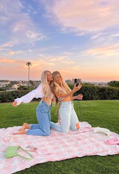 two beautiful women sitting on top of a blanket