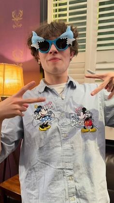 a young man wearing mickey mouse sunglasses and pointing to the side