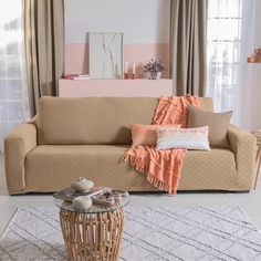 a living room with a couch, coffee table and rugs on the floor in front of windows