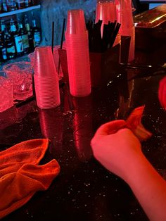 a person is cutting something with scissors on a table in front of some cups and bottles