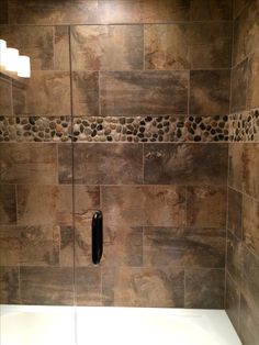 a walk in shower sitting next to a bath tub with rocks on the wall and floor